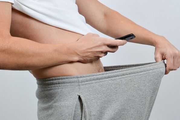 a man looks under his pants at an enlarged penis